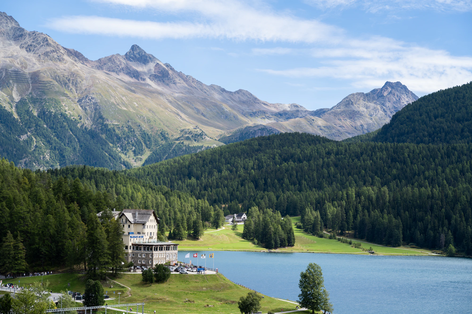 Albergo sulla riva di un lago alpino, tra i boschi e le montagne